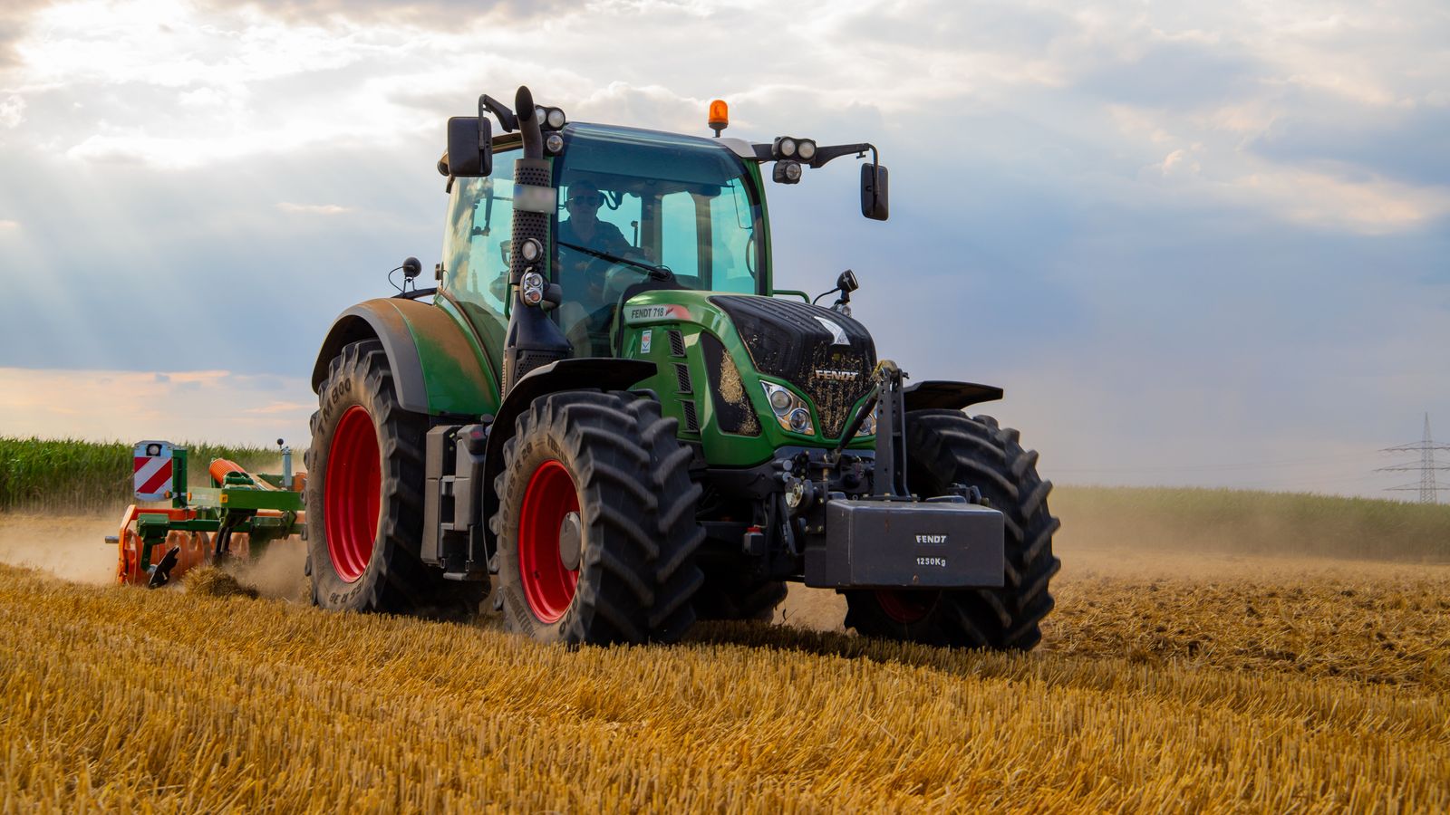 Traktor rolniczy na polu po zniwach - pofermentat jako nawoz organiczny z biogazowni rolniczej